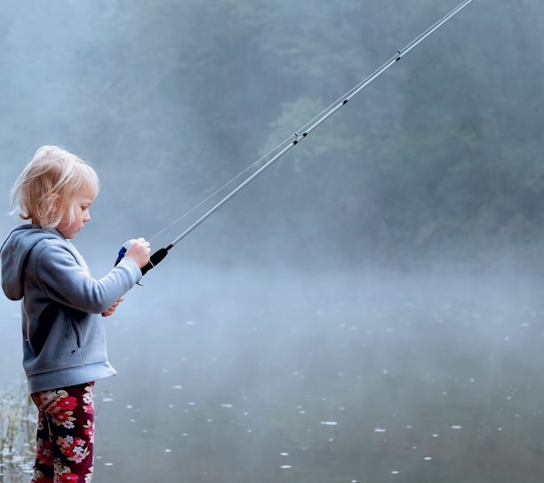 toddler wearing gray hoodie holding fishing rod