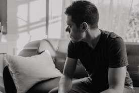 grayscale photography of man sitting on sofa