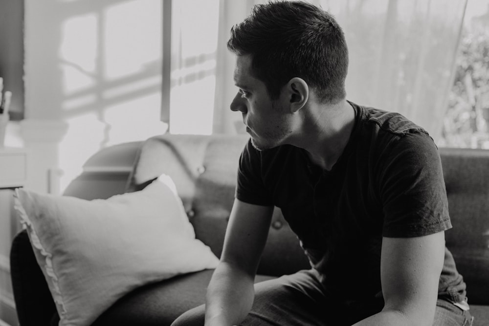 grayscale photography of man sitting on sofa