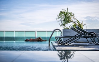 woman lying at pool beside fence during daytime