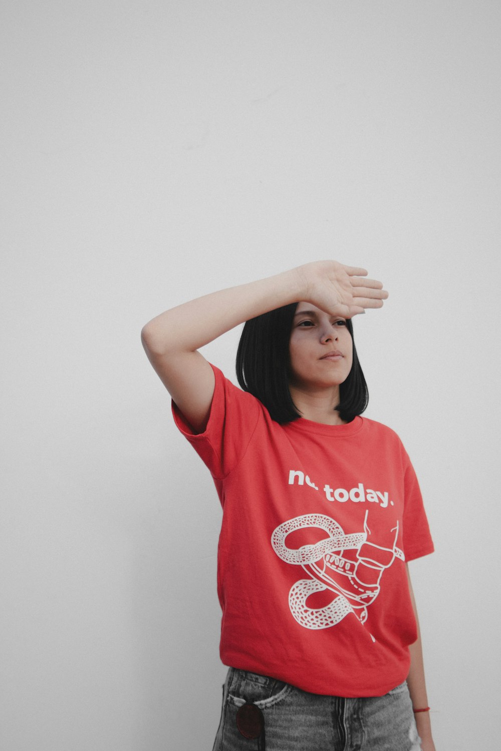 a woman in a red shirt holding her hands up to her head