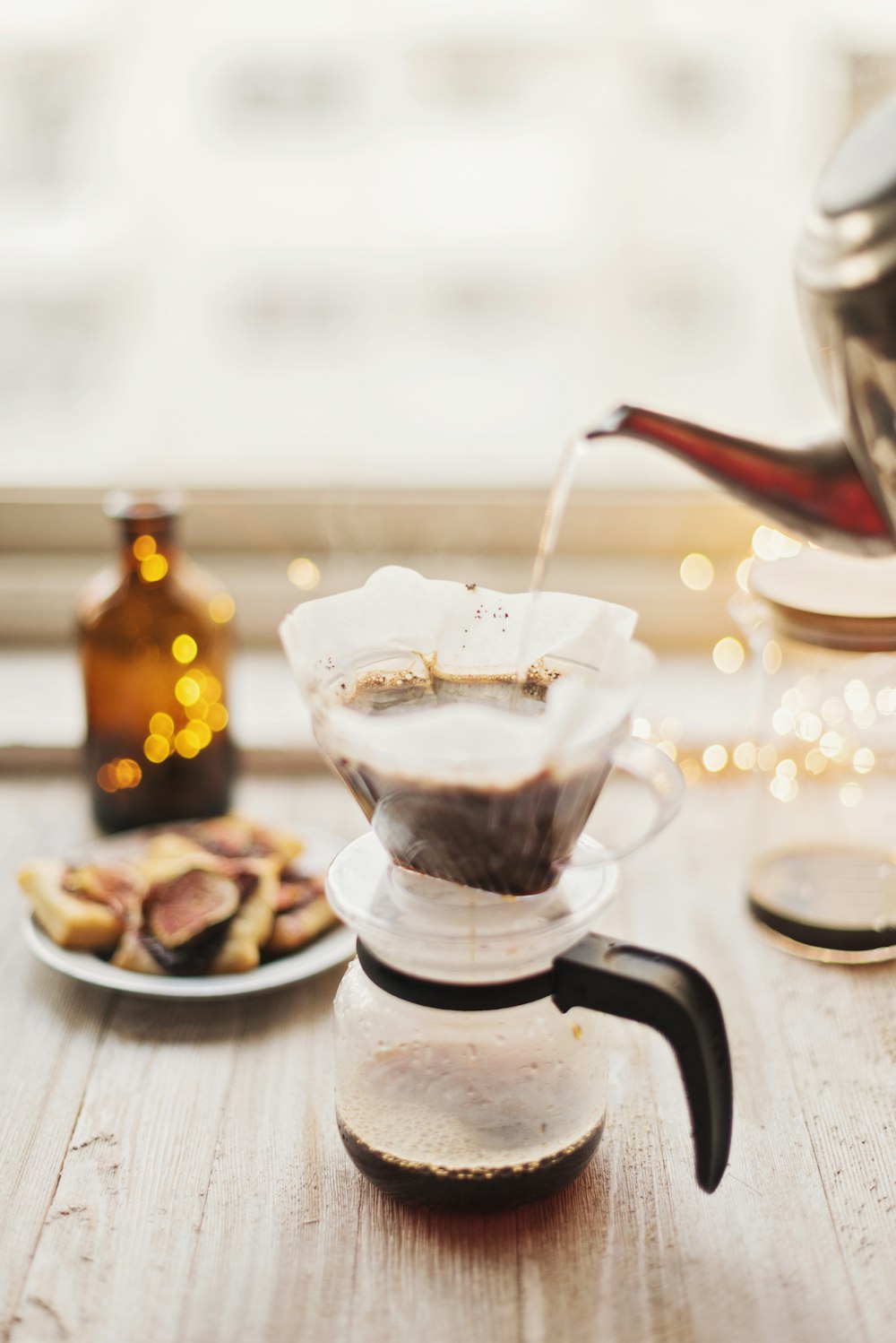 hot water from pot being poured into coffee carafe on table