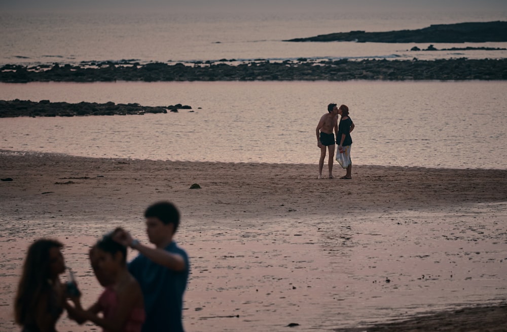 couple kissing on beach during daytime