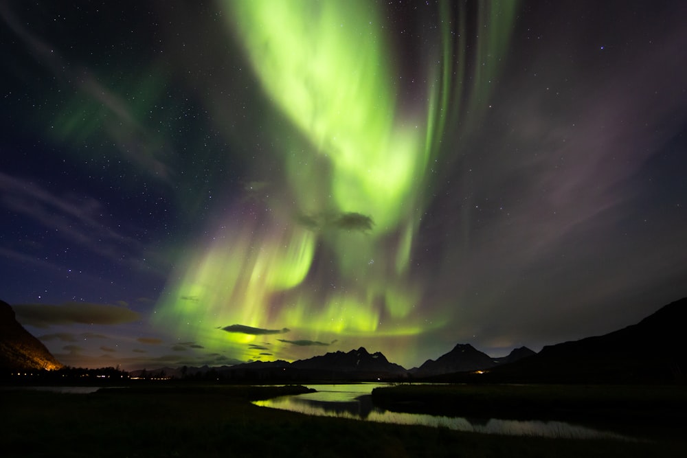 Aurora over body of water and mountain