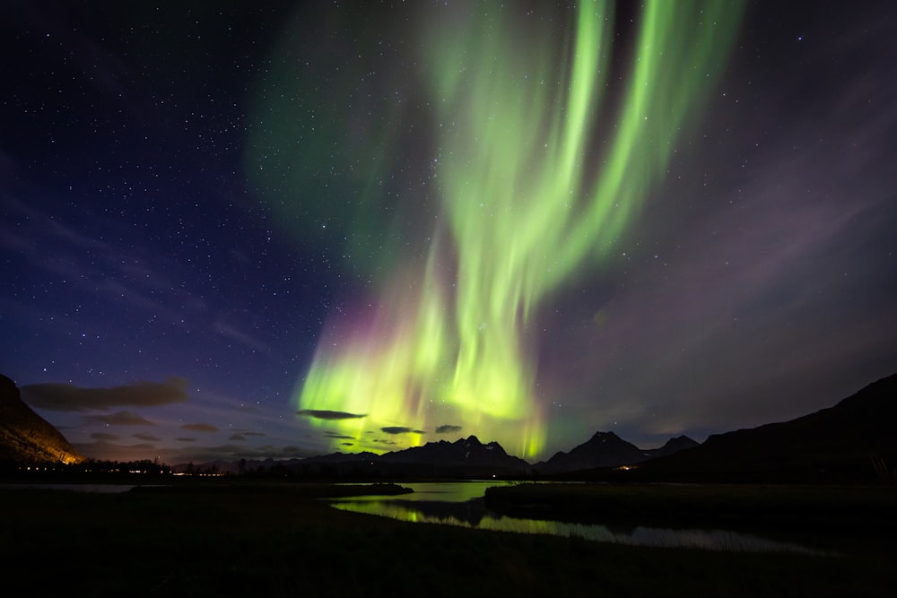 aurora over body of water and mountains