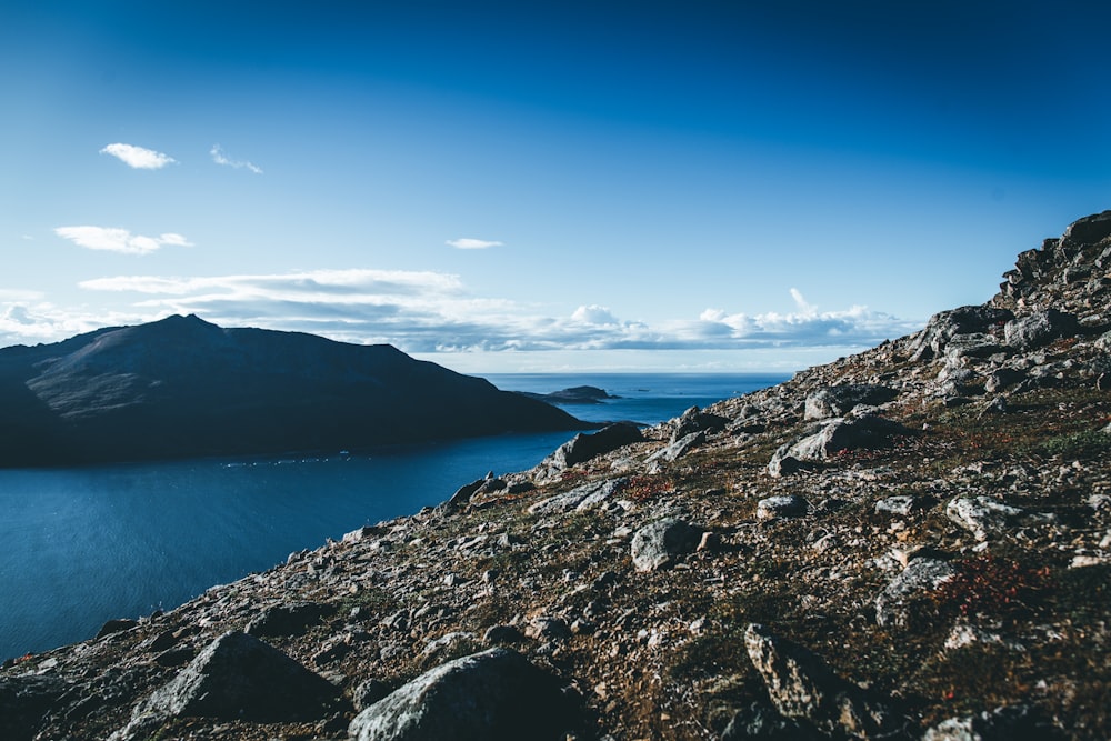 blue sea viewing mountain under blue and white sky during daytime