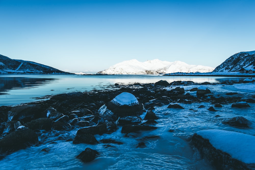 snow covered mountain and rock formation near body of water