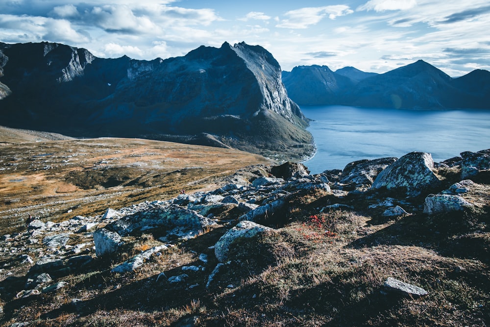 brown rocky mountain beside lake during daytime