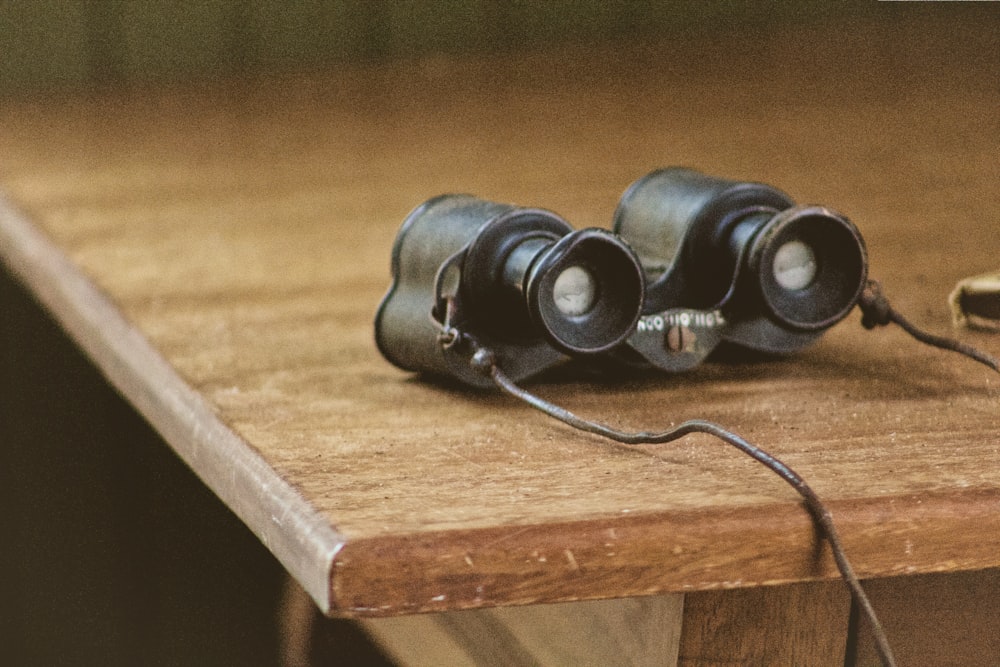 black binocular on brown wooden table