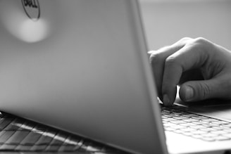 Close-up of hands typing on a laptop keyboard with a modern black and white theme.