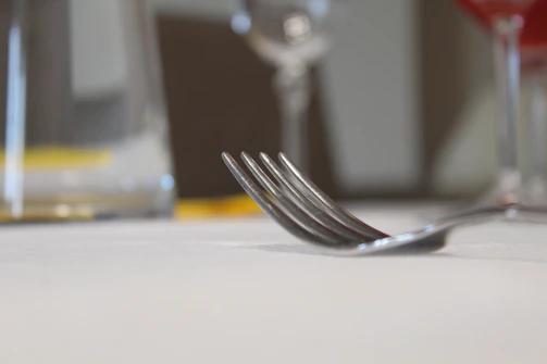 Close-up of a textured gray waterproof tablecloth under delicate glassware and silver cutlery, highlighting fabric detail.