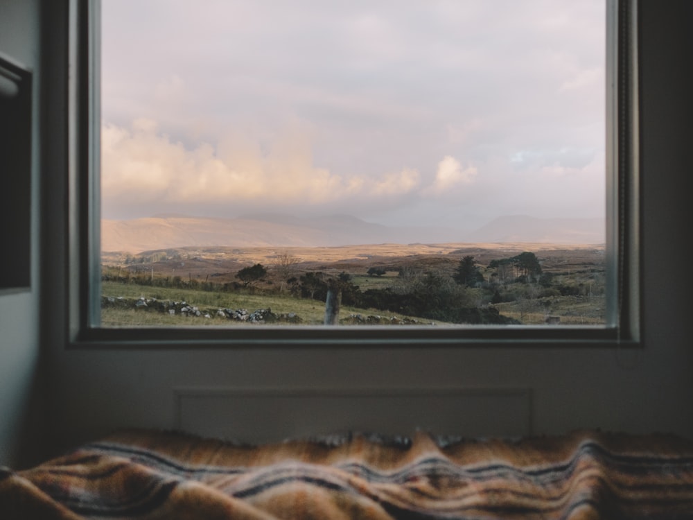 brown and white blanket beside with framed glass window