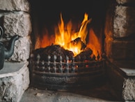 A rustic stone hearth glowing warmly with a gentle fire, surrounded by hand-thrown pottery.