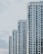 A series of modern high-rise apartment buildings with numerous windows and balconies, positioned side by side in a slightly staggered formation. The buildings appear to be well-maintained and have a uniform architectural style with a clean, minimalistic design.