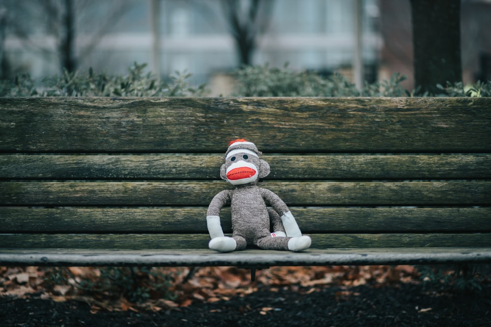Sock Monkey plush toy on brown wooden bench