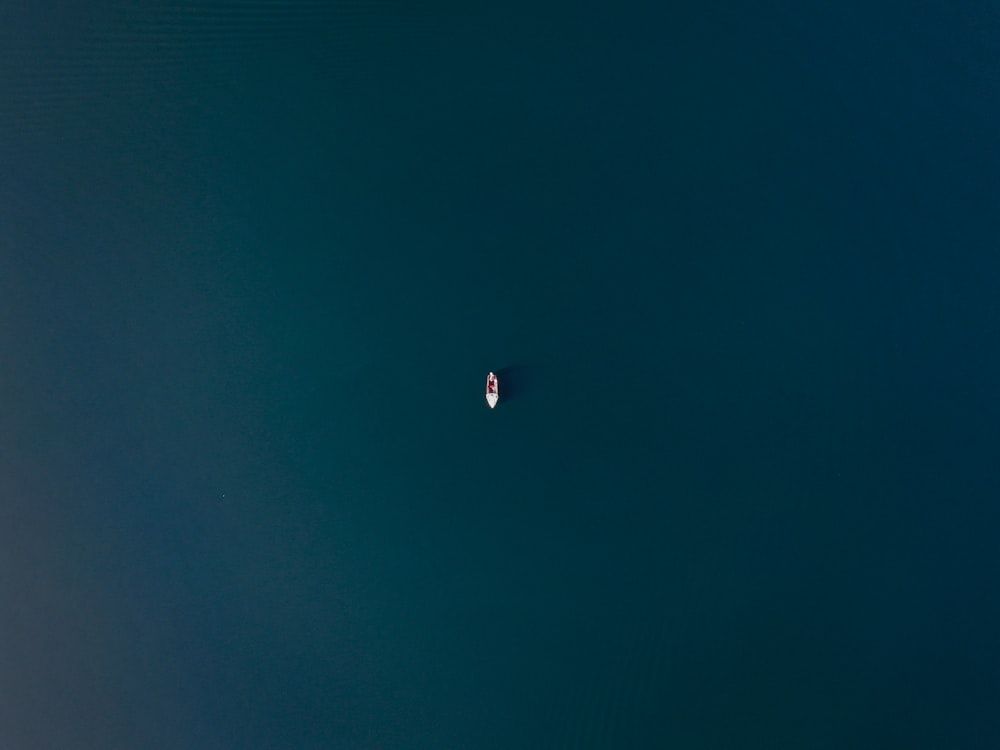 un petit bateau flottant sur un grand plan d’eau