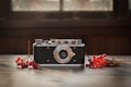 A vintage camera with a textured black body and silver details is placed on a wooden surface. Red berries and small branches are arranged artistically around the camera, while a soft, natural light filters through the window in the background.