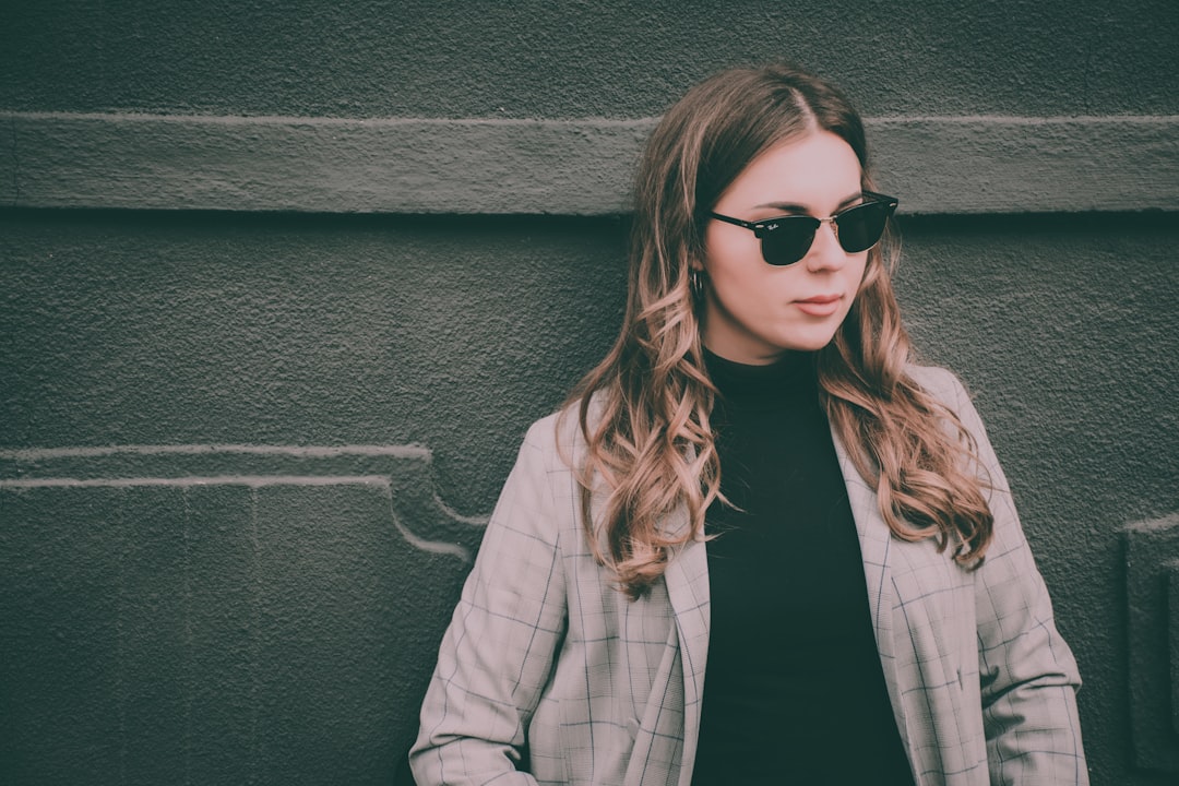 woman wearing gray blazer leaning on black surface