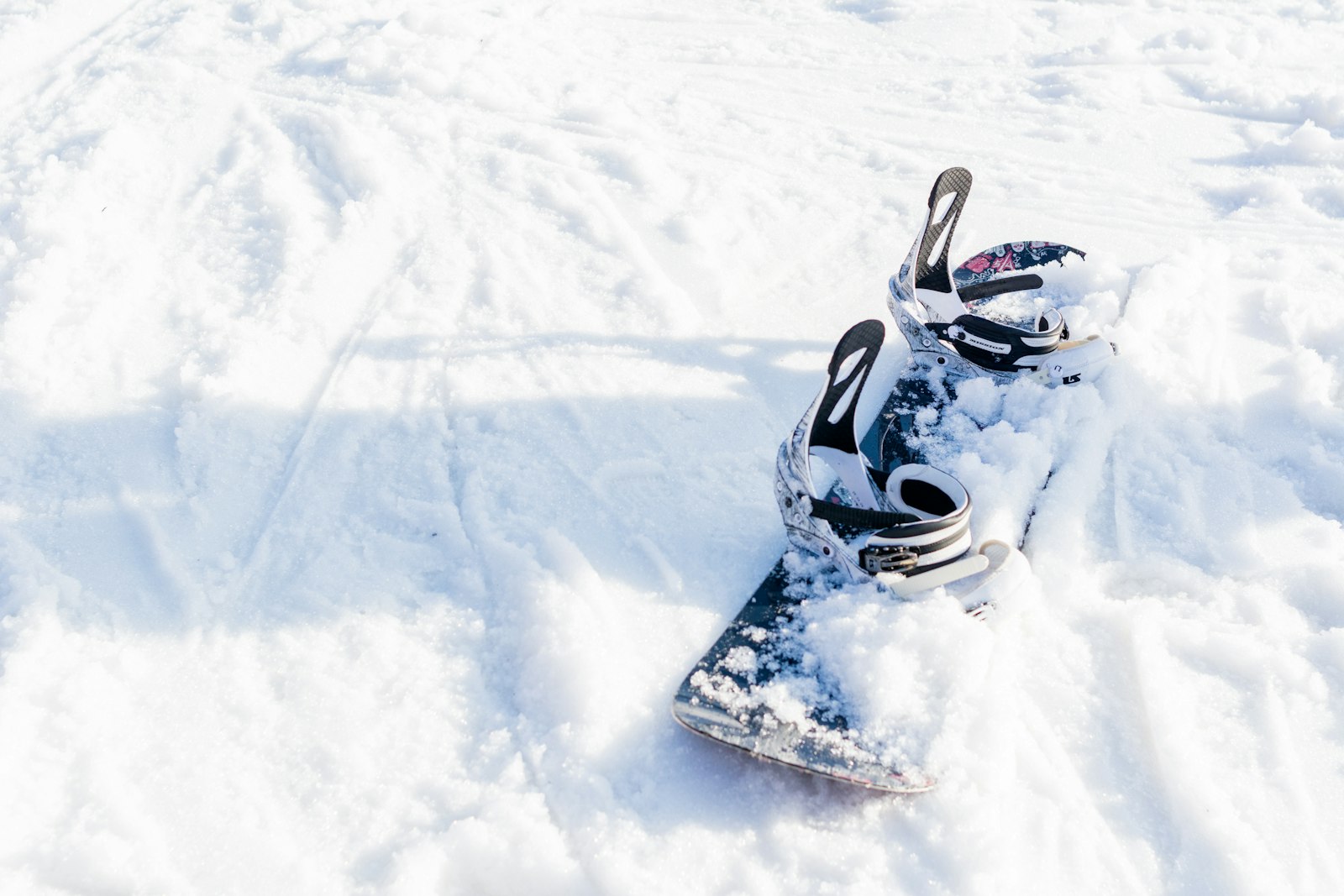 A snowboard on snow with mounted bindings