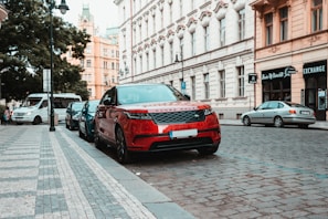 red range rover parked near building during daytime