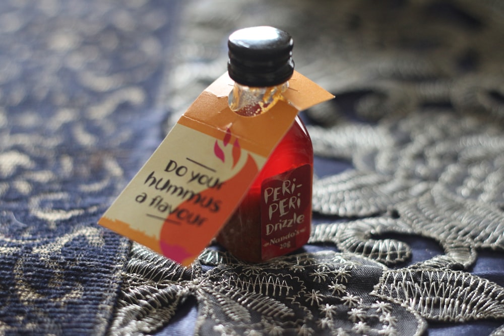 Peri-Peri Drizzle bottle on black and brown floral textile