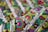 An intricate textile with vibrant embroidery featuring circular and spiral patterns in various colors. The fabric displays a complex design with layers of green, red, purple, and blue threads against a textured background.