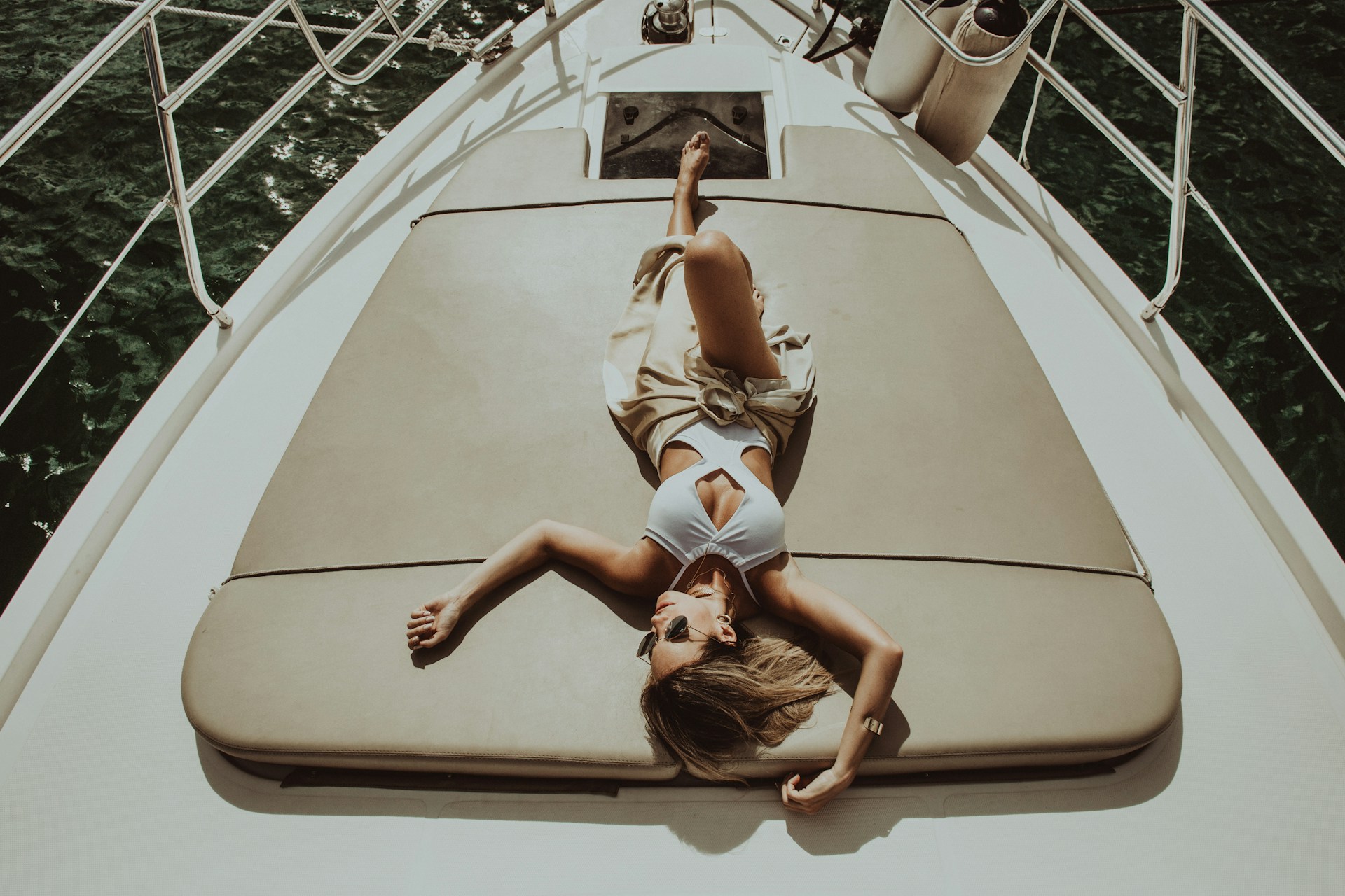 woman lying on gray mat on white boat