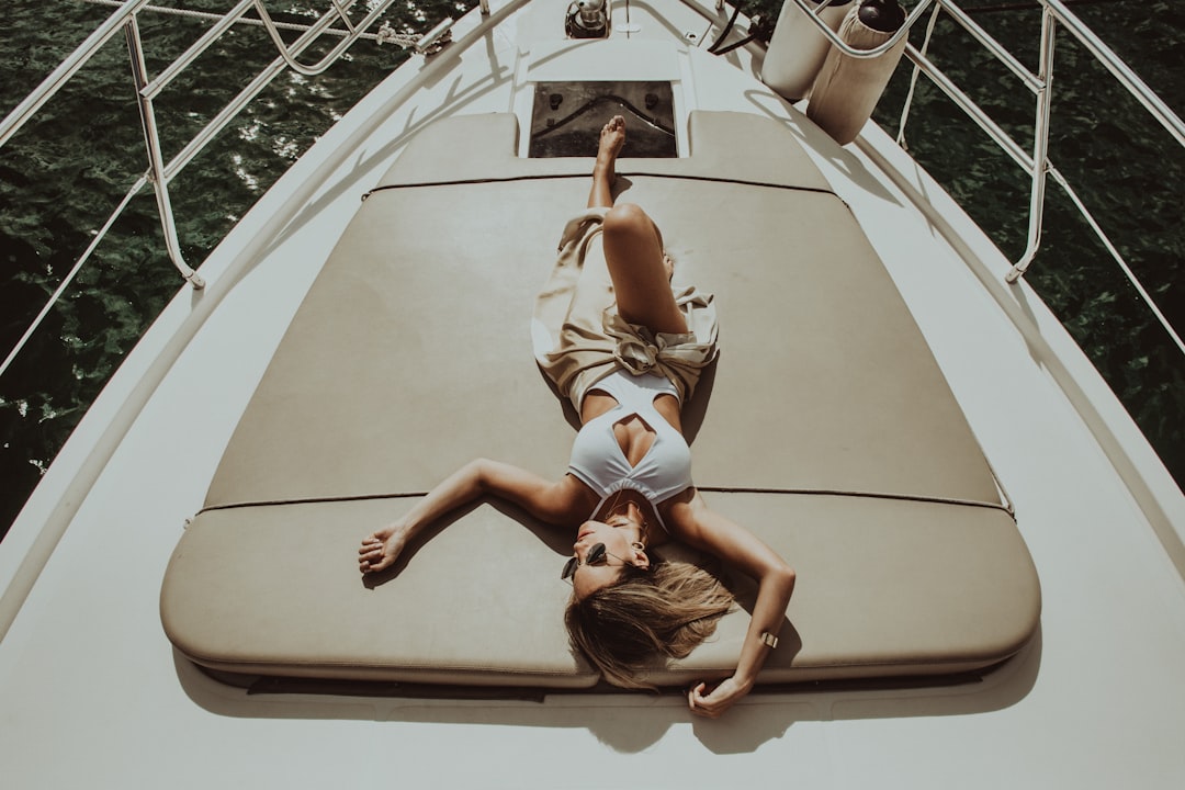 woman lying on gray mat on white boat