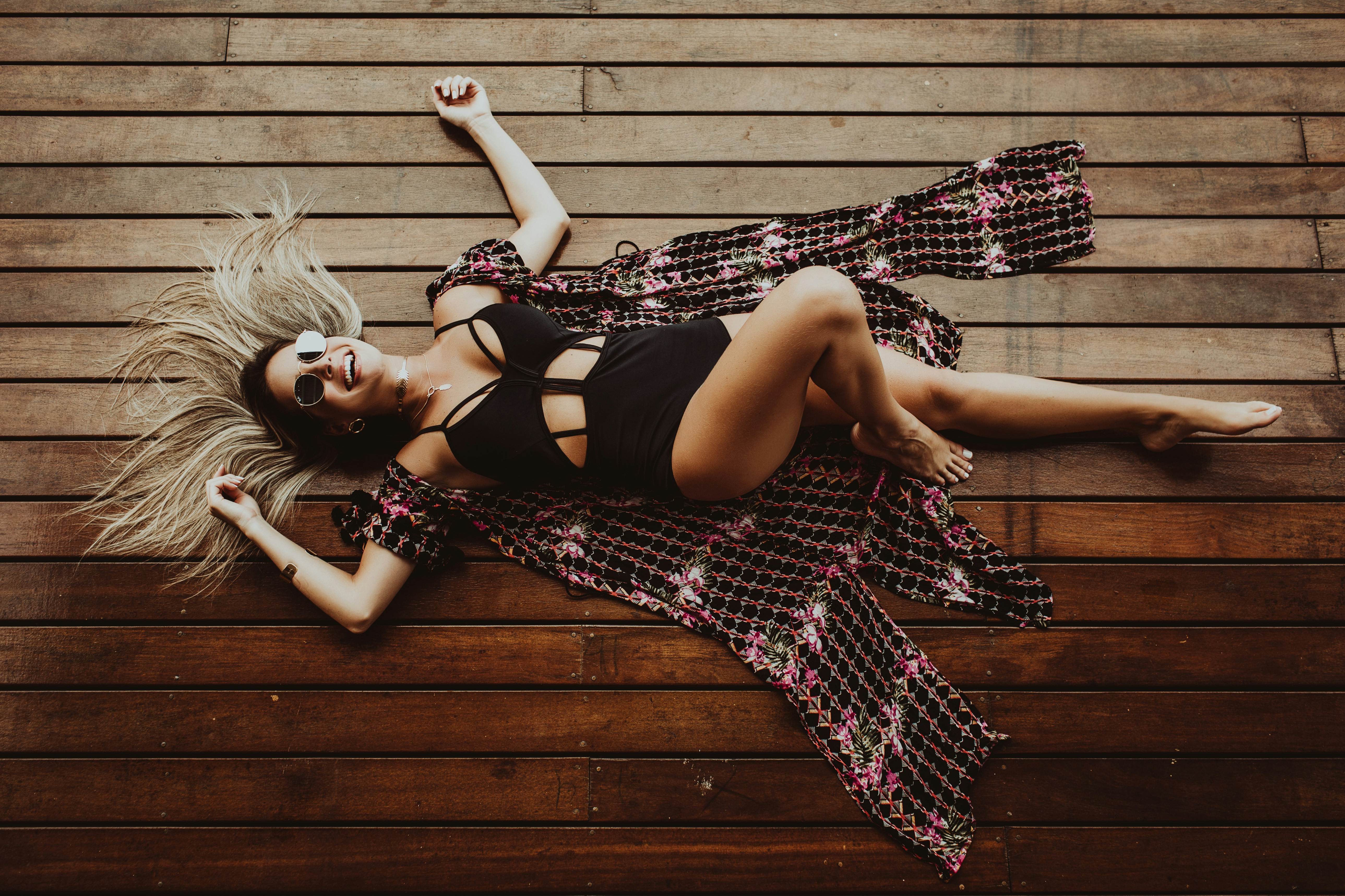 smiling woman lying on brown wooden surface