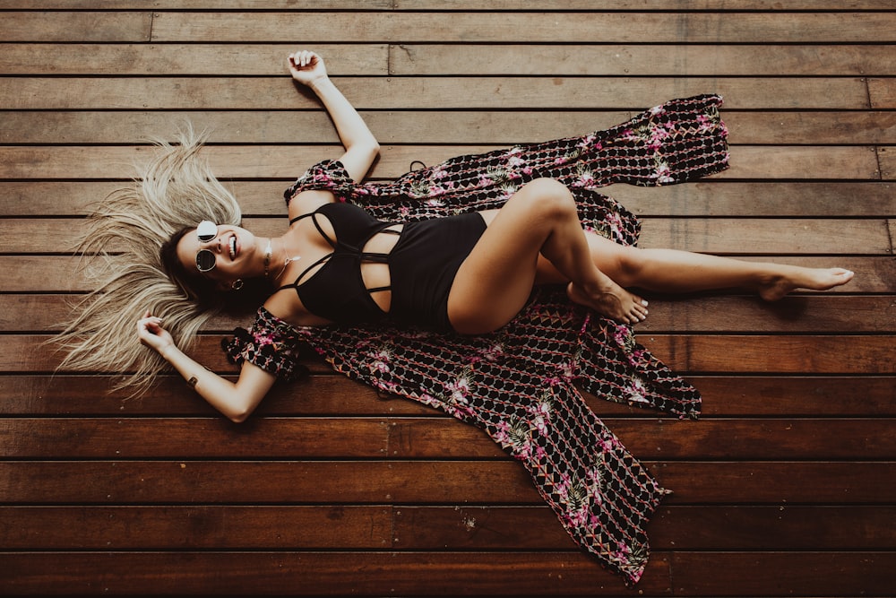 smiling woman lying on brown wooden surface