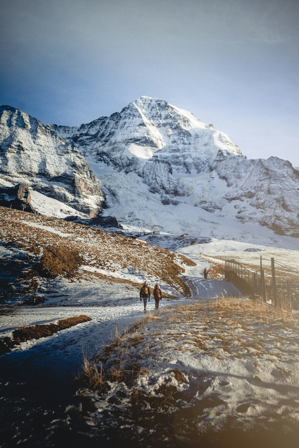 two persons walking towards snow hills