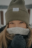 Side profile of a person bundled up in a brushed knit hat and scarf, with snow gently falling.