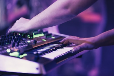 Hands programming synthesizers with dynamic light effects.
