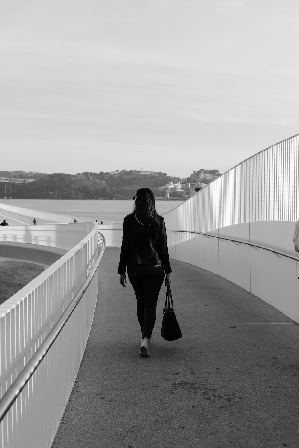 grayscale photo of woman walking on pathway