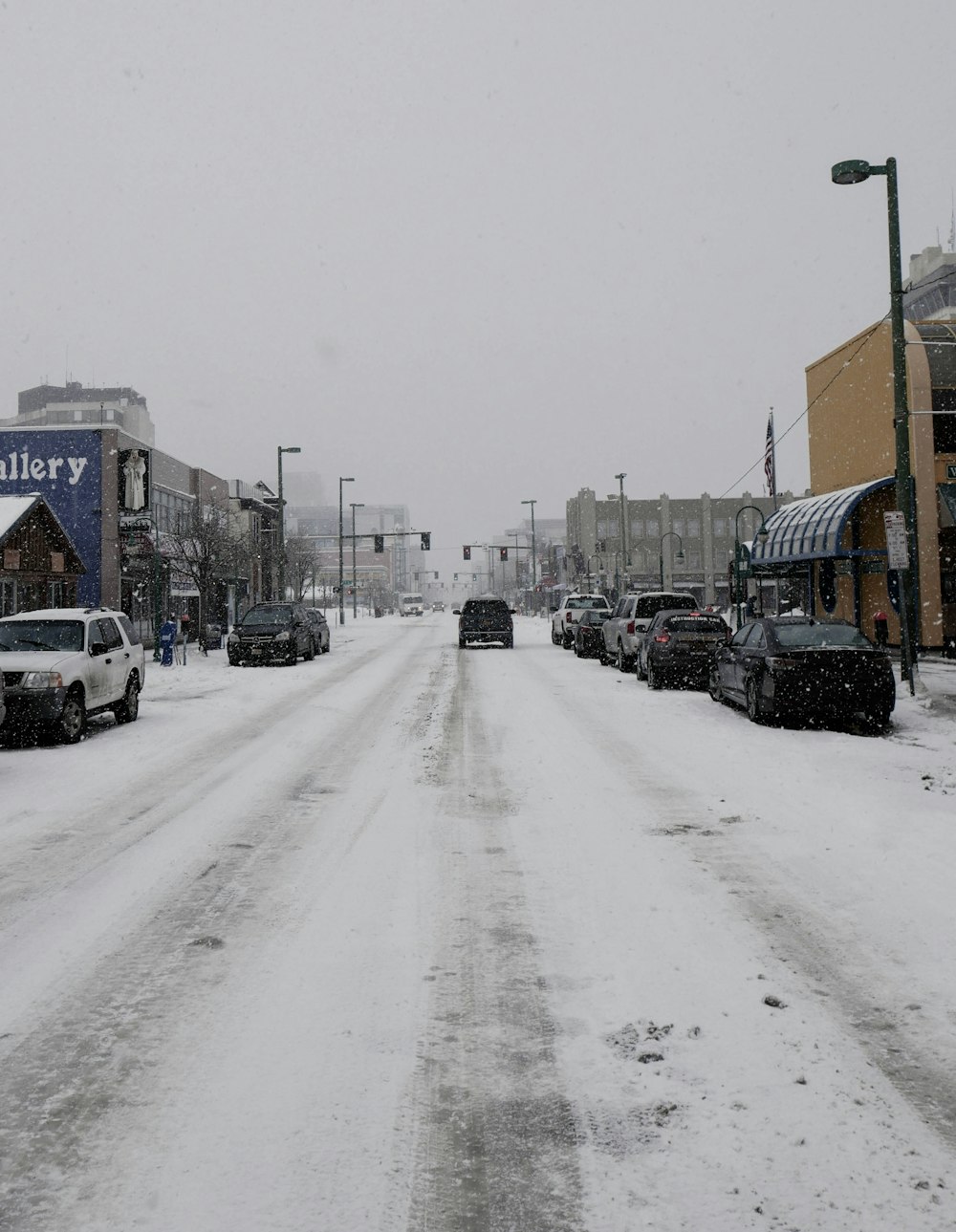 snow covered vehicles parked on road