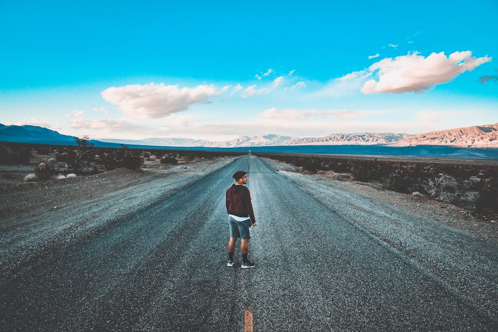 man standing in the middle of road during daytime