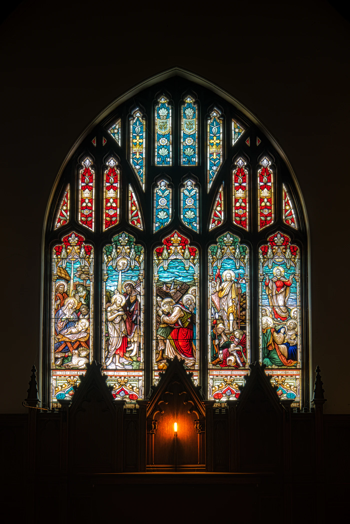Tall stained glass windows glowing above a church altar