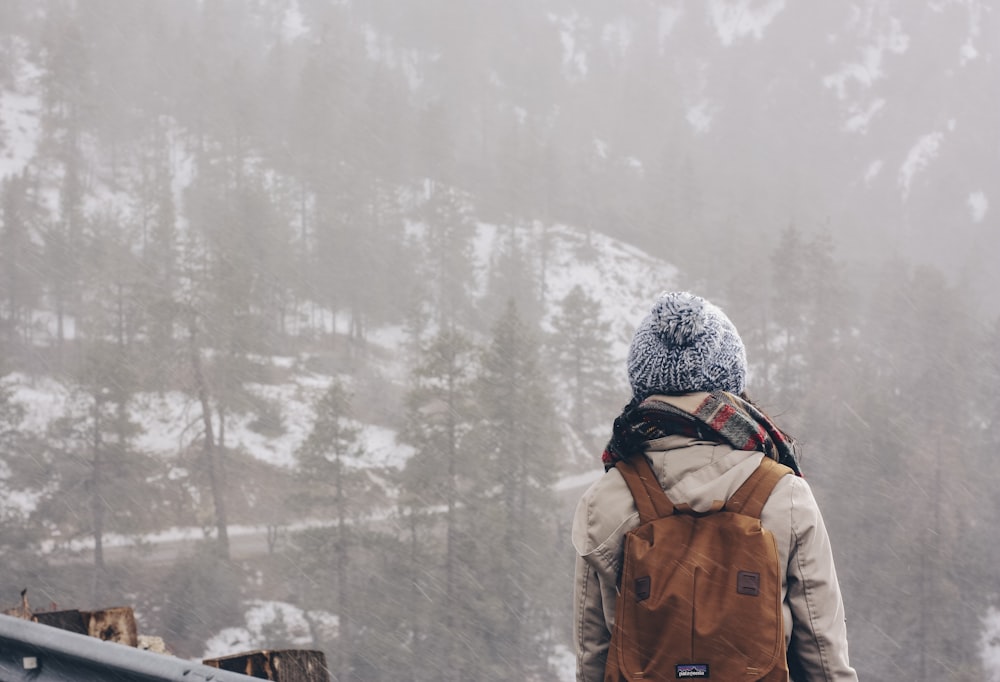 person wearing gray bobble hat carrying backpack