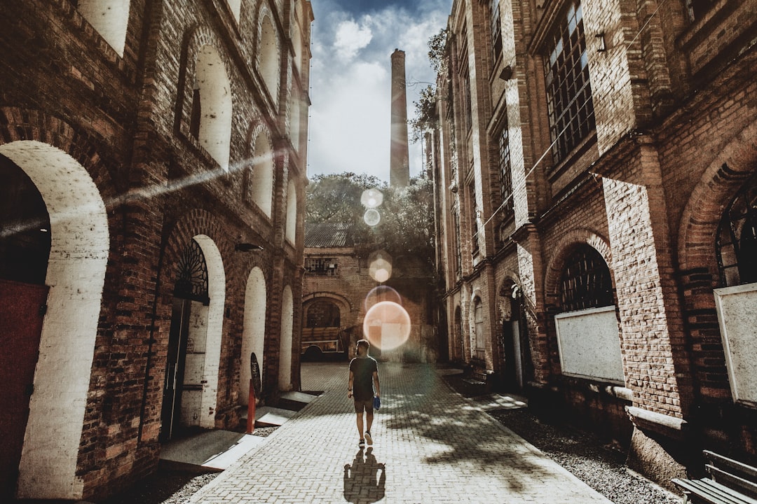 man walking in between bricked building at daytime