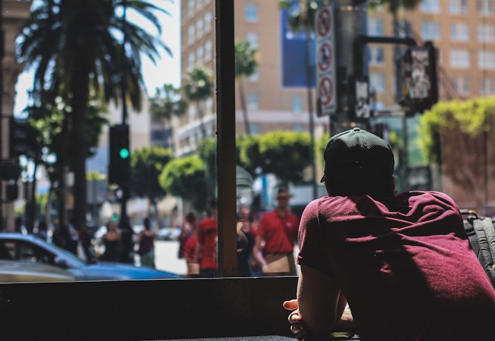 A discreet agent observing a busy urban street from a shaded corner.