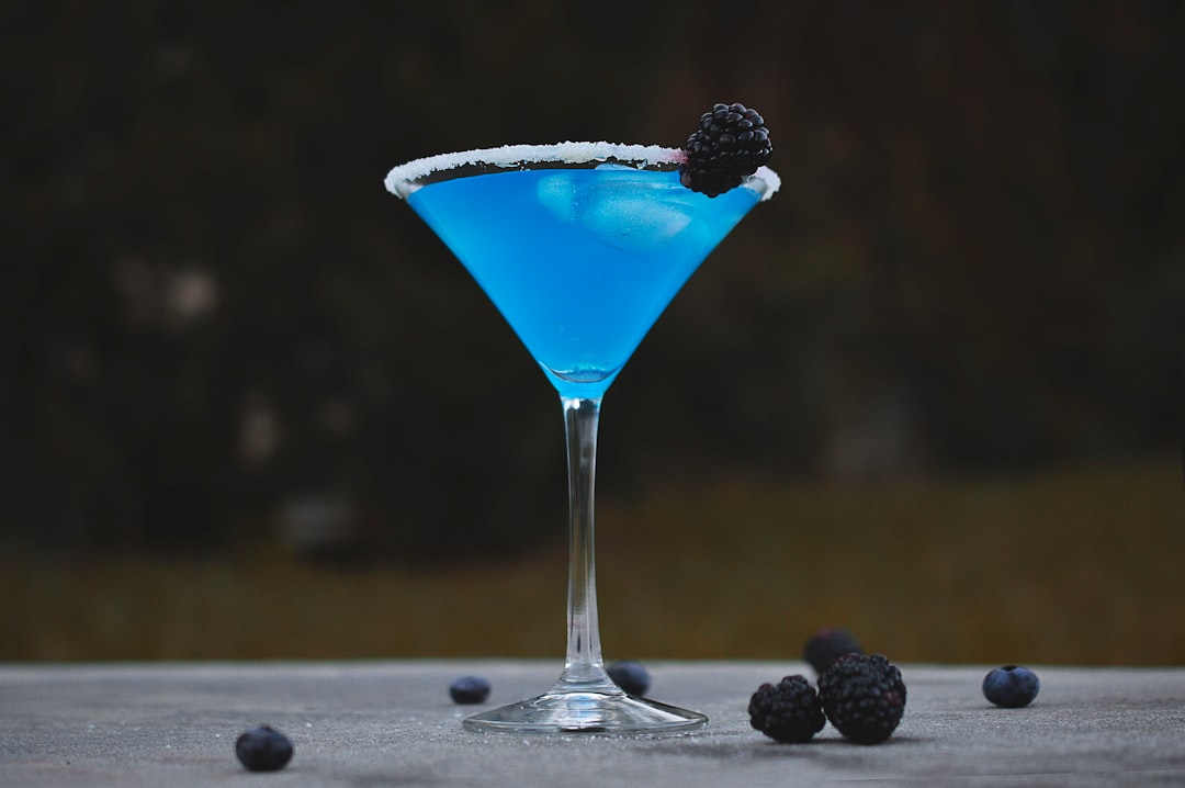 martini glass with mulberry and blue liquid