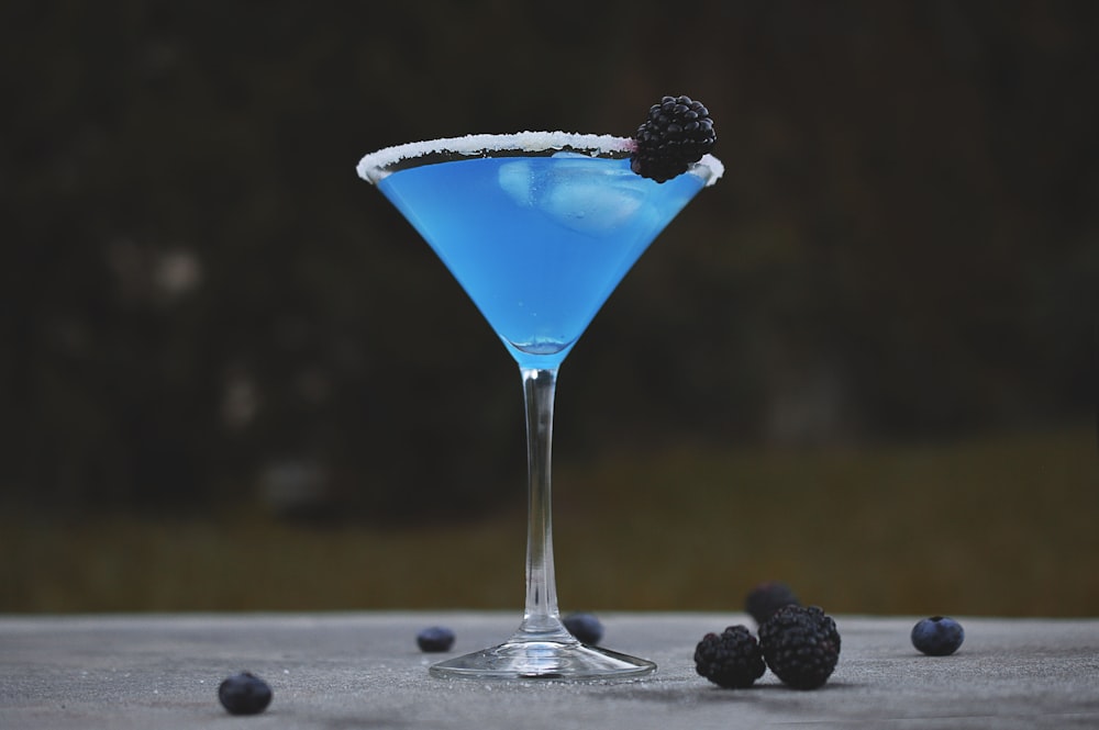 martini glass with mulberry and blue liquid
