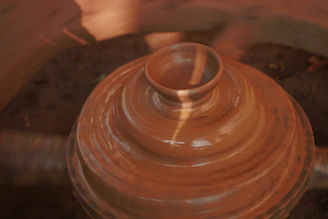 Close-up of a vibrant stoneware mug being shaped on a potter's wheel.
