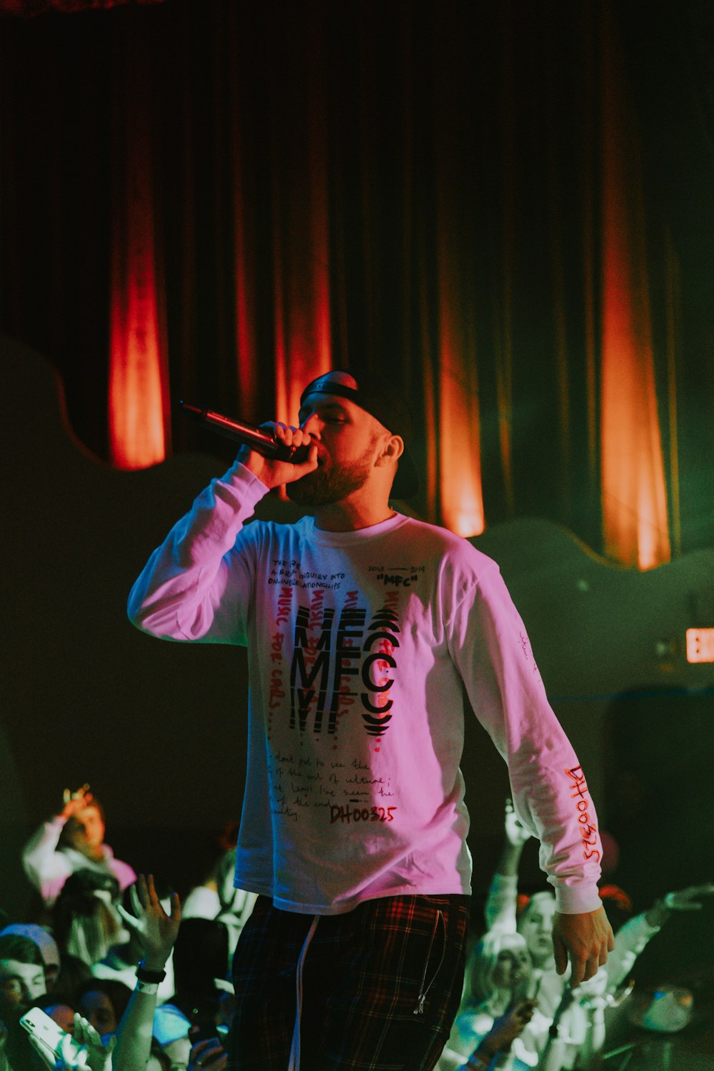 man holding microphone wearing white and black MFC long-sleeved shirt