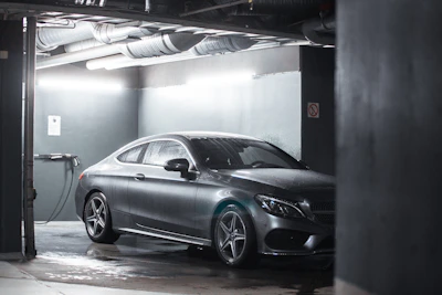 A sleek black luxury car parked in a spotless, modern garage with golden accents.