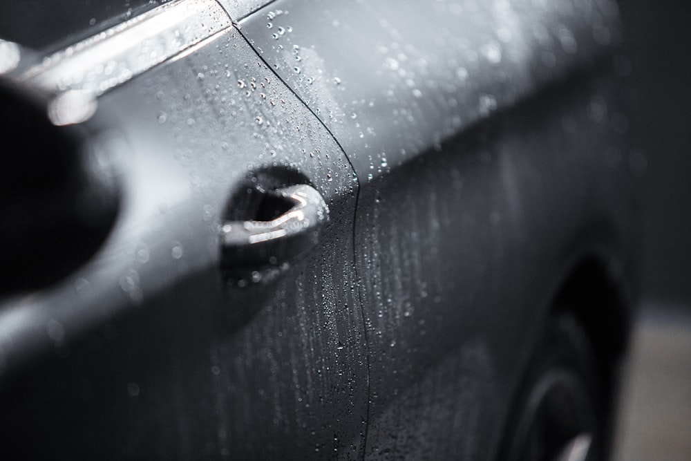Eine Nahaufnahme eines schwarzen Autos mit Regentropfen darauf