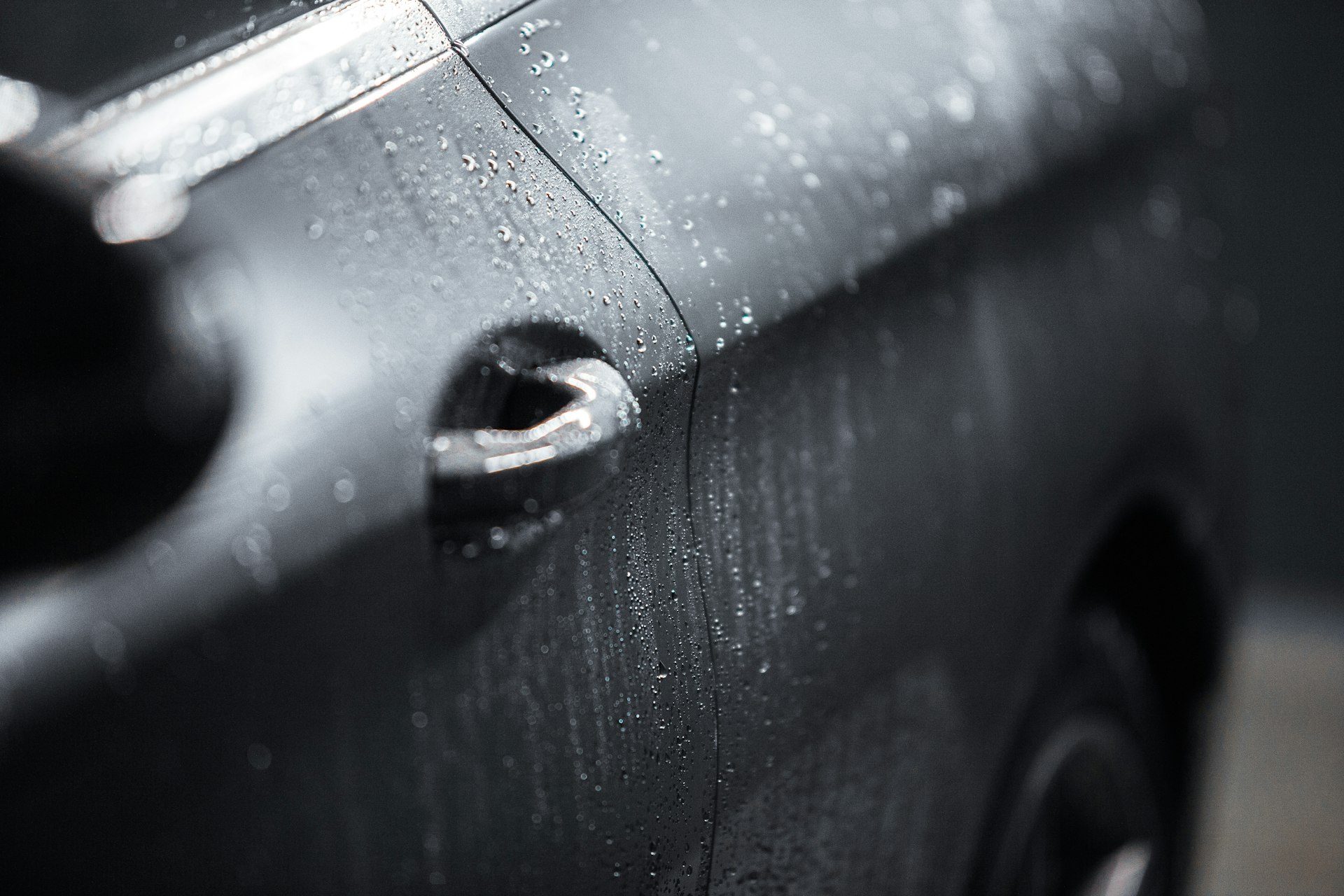 Water beading on the ceramic-coated door of a dark grey car