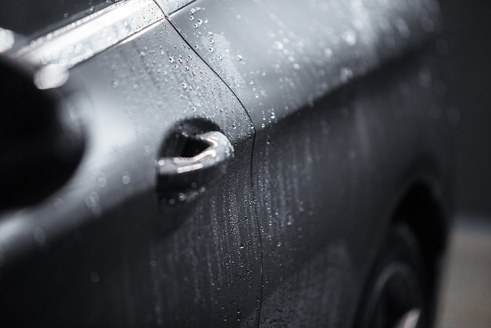 a close up of a black car with rain drops on it