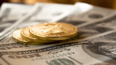 three round gold-colored coins on 100 US dollar banknotes