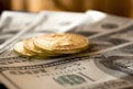 three round gold-colored coins on 100 US dollar banknotes